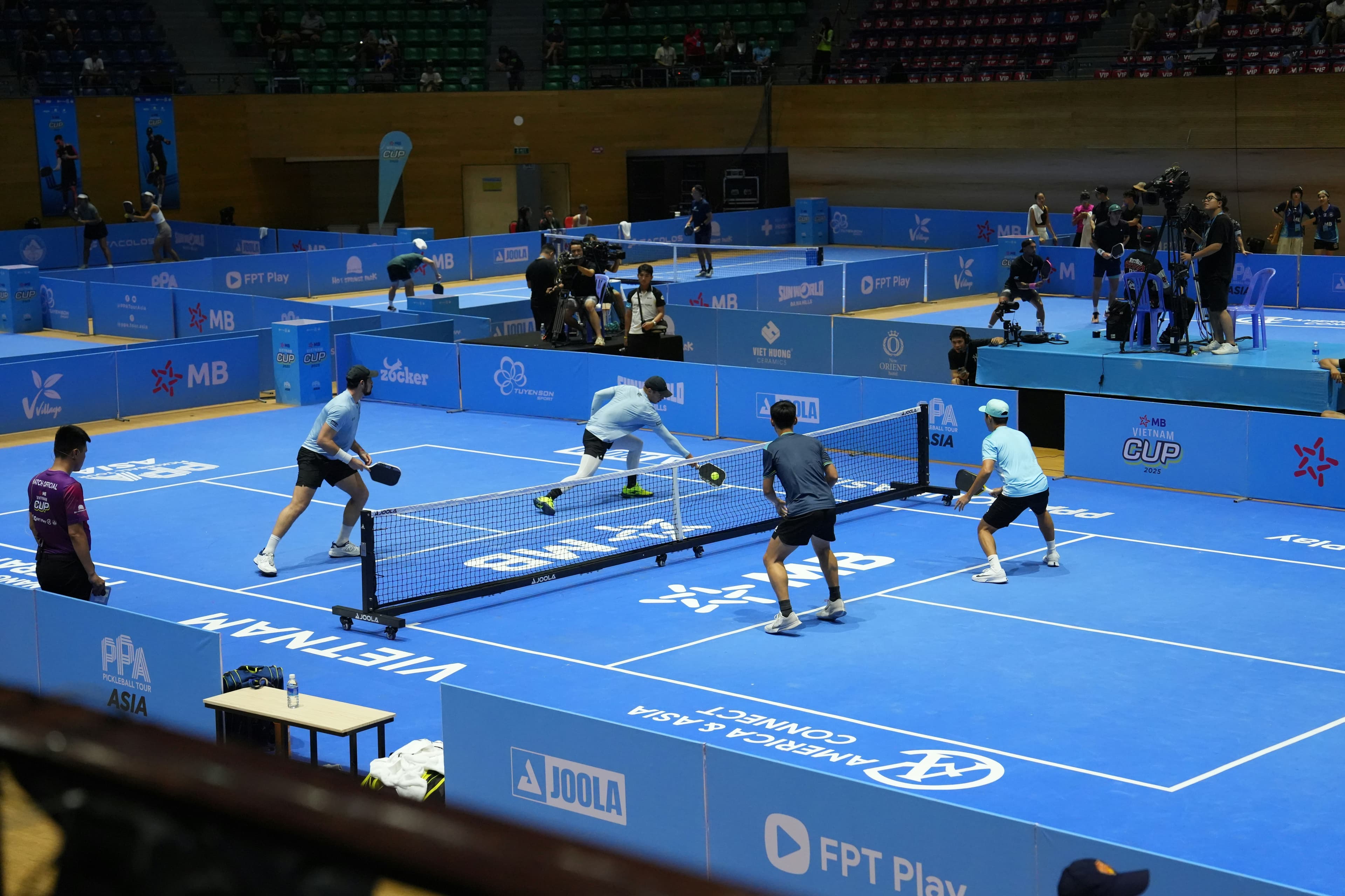 Doubles matches on a row of indoor pickleball courts